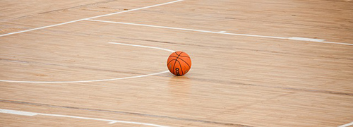Image of basketball on gym floor.